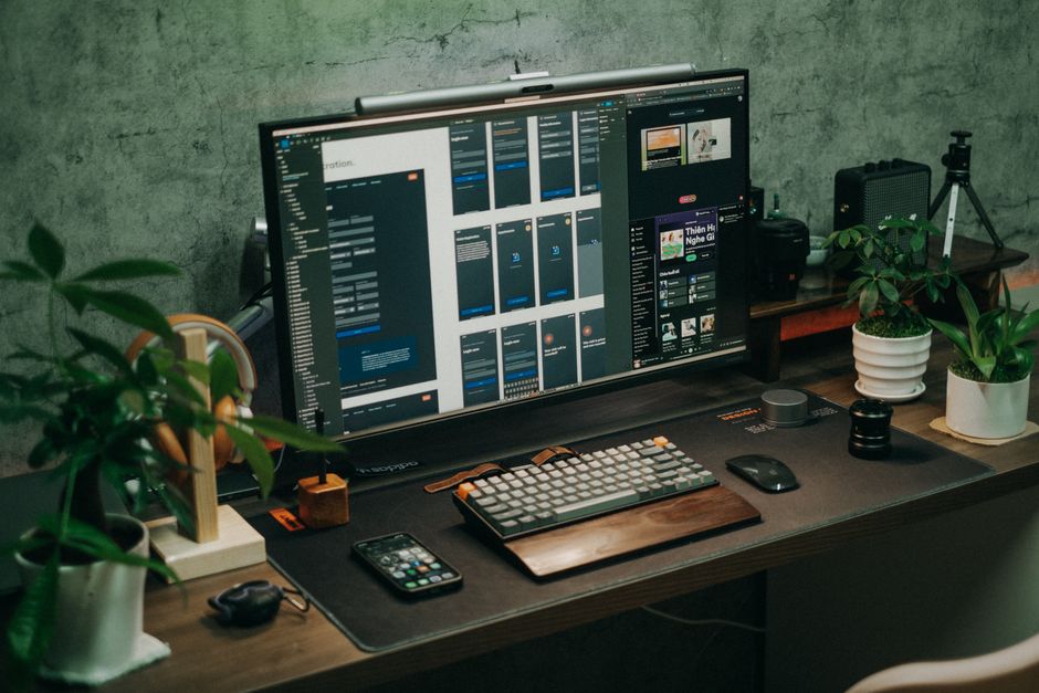 A tidy office desk featuring a computer monitor, keyboard, and plants